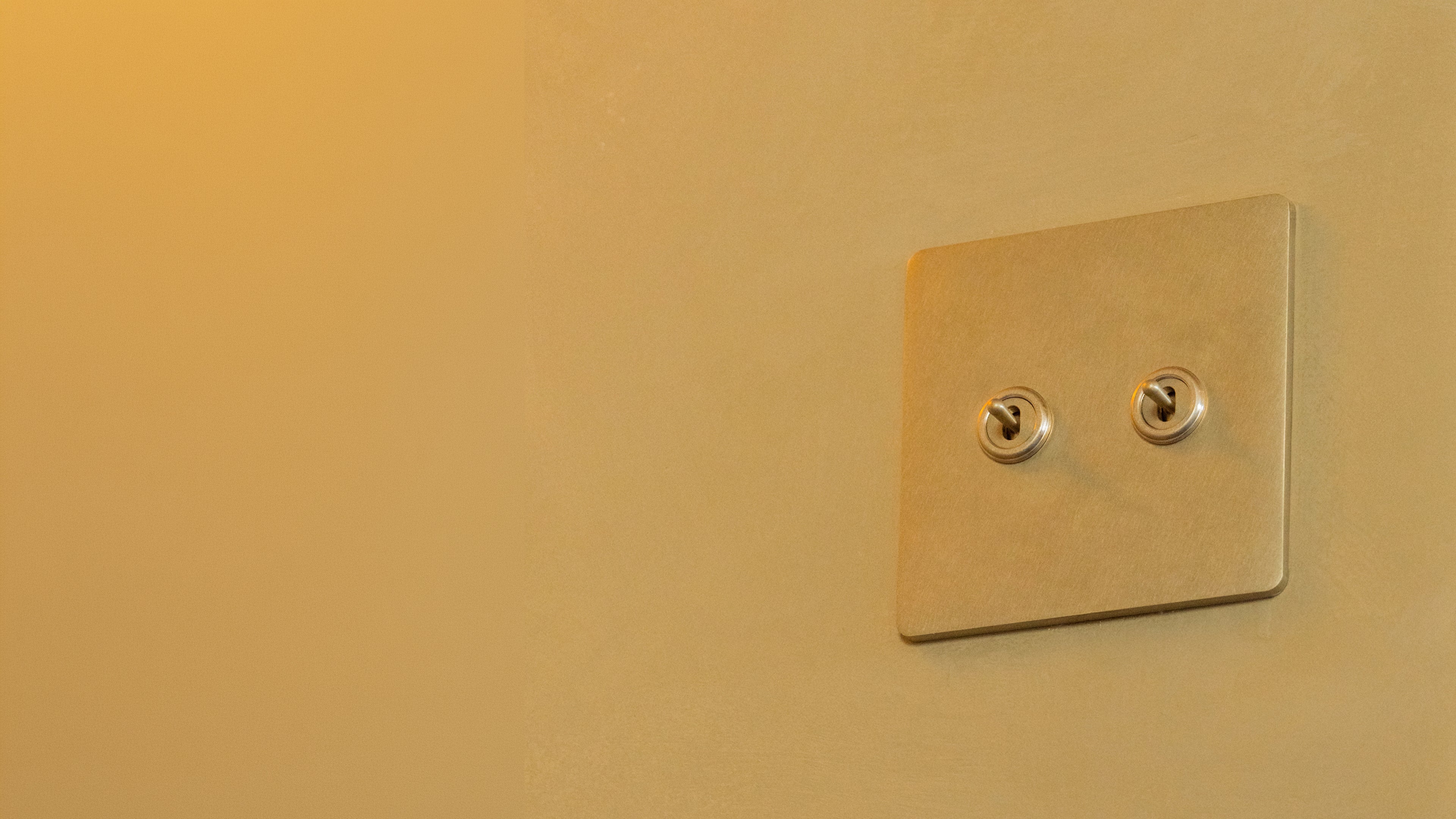 Corston brass toggle light switch on a warm plaster wall